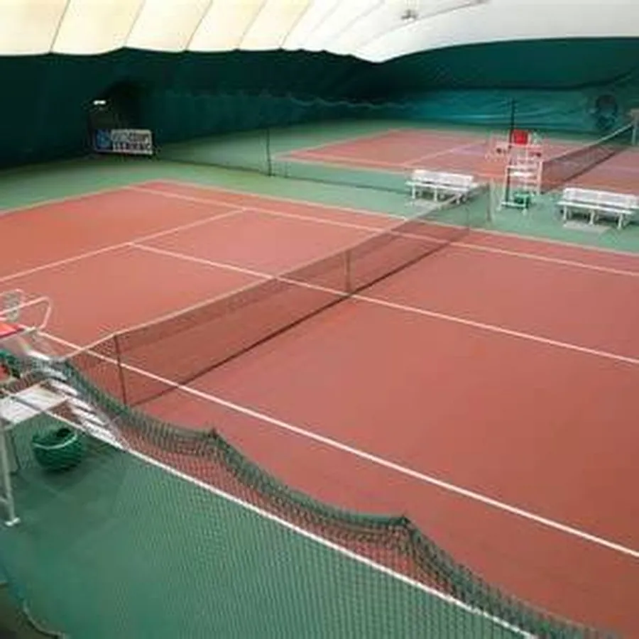 Красное игровое покрытие и сетка на крытом корте Tennis.ru